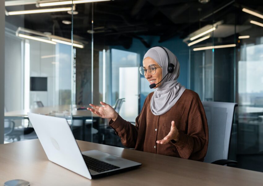 Online teaching. Young Muslim woman in hijab and headset, teacher sitting at desk in office in